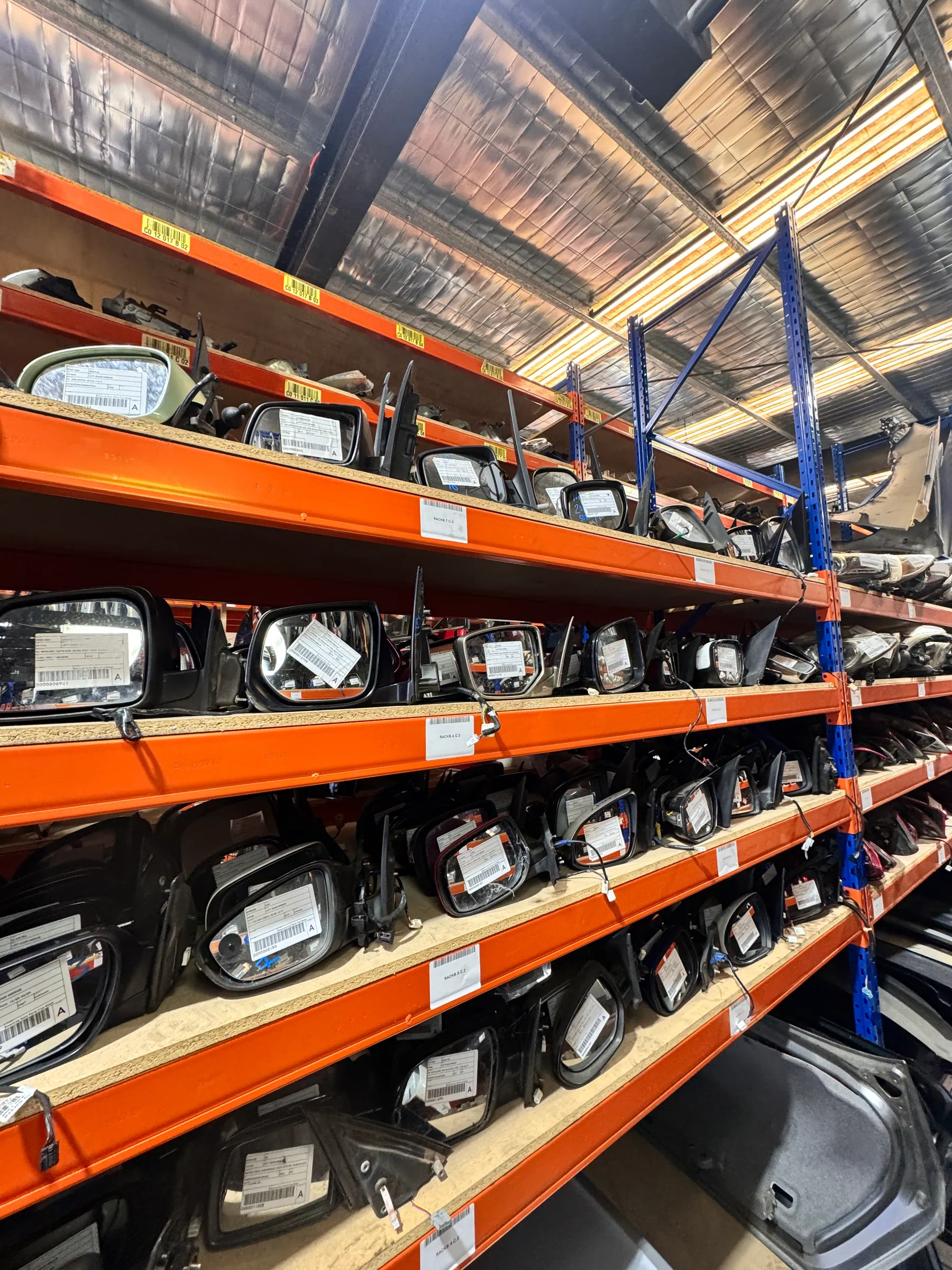 Side mirrors arranged across multiple warehouse shelves.