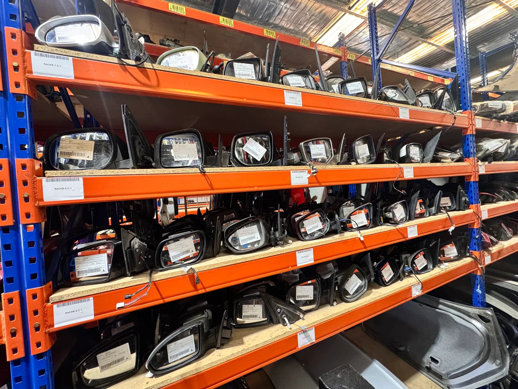 Rows of side mirrors stored and labelled by vehicle fitment.