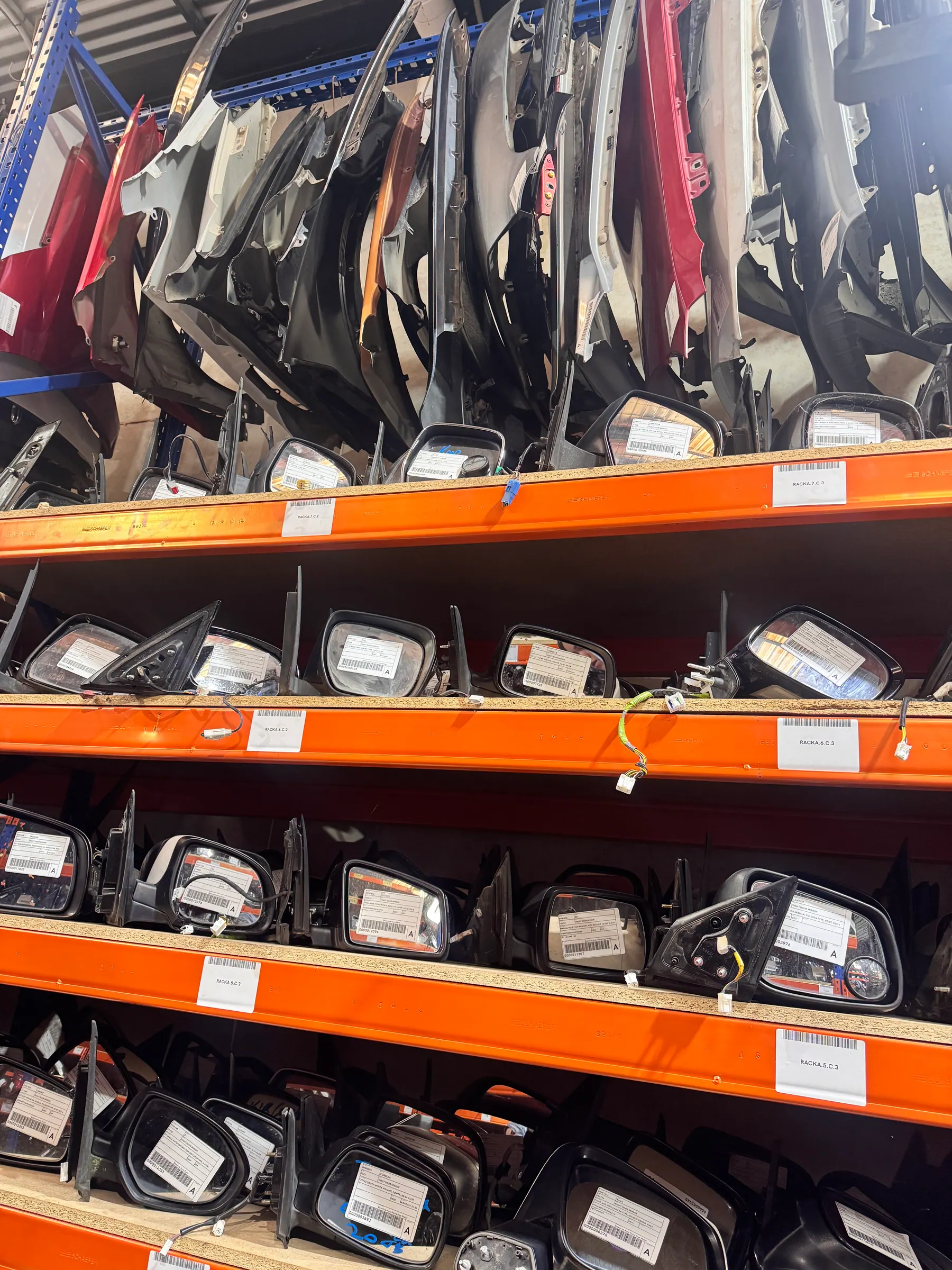 Close-up of labelled side mirrors on PartsBase warehouse racks.