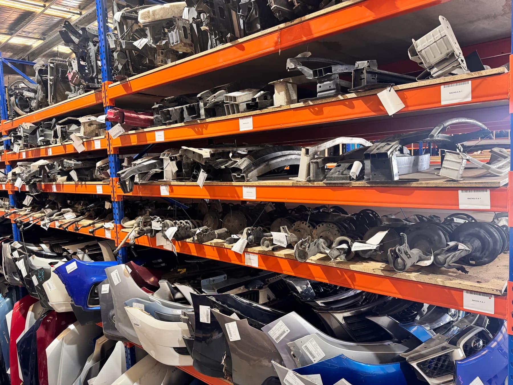 Warehouse shelving with long rows of vehicle bumpers and panels.