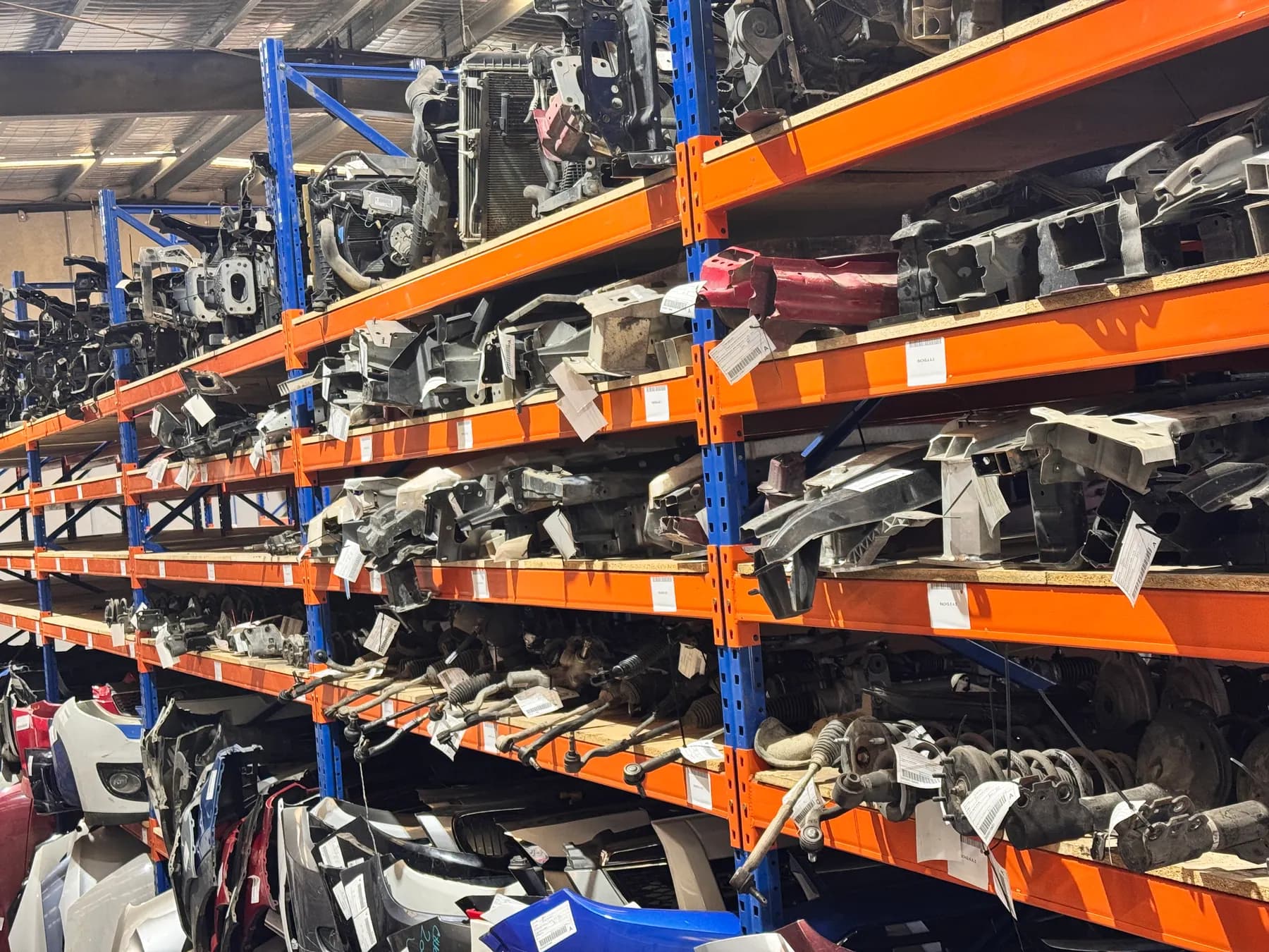 Vehicle panels, bumpers and dismantled parts on high storage racks.